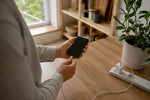 Smartphone, das mit einem Schnellladekabel auf einem weißen Tisch verbunden ist