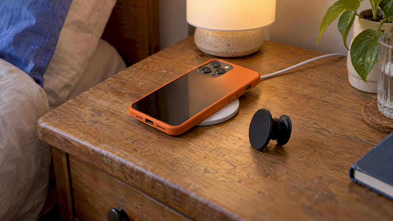Abgenommener PopGrip liegt neben einem iPhone auf dem Ladegerät